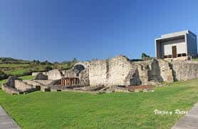 Fachada de las ruinas arqueológicas con el museo contemporáneo al fondo bajo cielo despejado