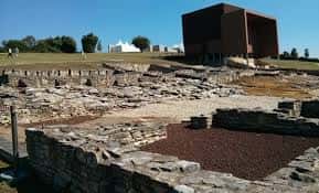 Detalle de los muros de piedra y el edificio de exposición en primer plano
