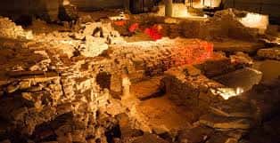 Detalle de las estructuras de piedra y muros antiguos iluminados en el interior del museo