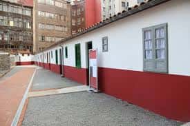 Vista exterior del patio de la Ciudadela de Celestino Solar con fachada blanca y base roja