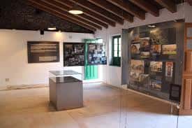 Interior del museo con vitrinas expositivas y techo de vigas de madera