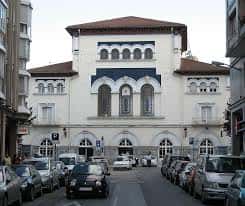 Edificio de Correos en Vitoria con fachada blanca y arcos decorativos, ubicado en una calle con vehículos estacionados
