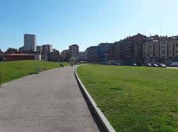 Sendero peatonal en los Jardines del Tren de la Libertad con zonas verdes y edificios urbanos