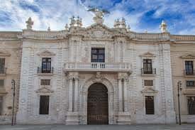 Fachada principal de la Real Fábrica de Tabacos en Sevilla, con detalles neoclásicos y esculturas en la parte superior