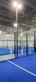 Vista interior de las pistas de pádel del Iron X Deluxe Padel Club con iluminación profesional y suelo azul