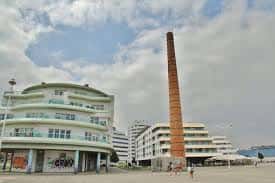 Plaza abierta frente a edificios curvos y la icónica chimenea de Poniente en Gijón