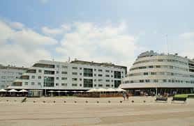 Explanada de Poniente con terrazas de cafeterías y arquitectura moderna bajo cielo parcialmente nublado