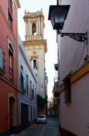 Vista de la torre de la Iglesia de San Bartolomé desde una calle estrecha de Sevilla