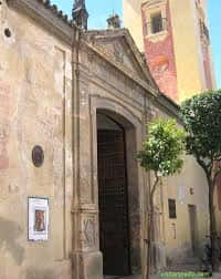 Fachada lateral de la Iglesia de San Bartolomé con entrada arqueada y árbol