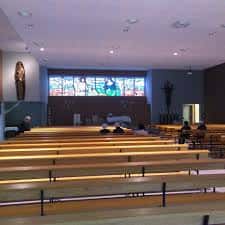 Interior de la Parroquia Santa María Josefa con bancos de madera y vitrales modernos