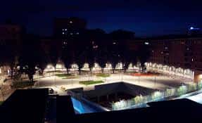 Vista nocturna de la plaza con iluminación ambiental y estructura subterránea visible