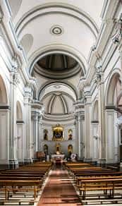 Interior de la iglesia con nave central, bóvedas blancas y altar principal decorado