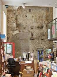 Detalle del interior de la librería con pared de ladrillo antiguo y zona de recepción, ideal para eventos culturales