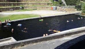 Actividad recreativa en la piscina natural de Os Peares con bañistas y flotadores