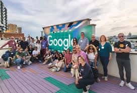 Grupo de empleados reunidos en terraza con logo de Google al fondo