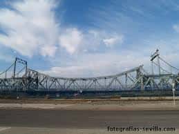 Panorámica del Puente de Alfonso XIII con cielo azul y nubes, destacando su longitud y diseño industrial