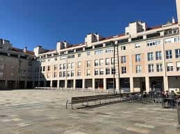 Vista diurna de la Plaza de Zumaia con edificios de fachada clara y bancos en primer plano