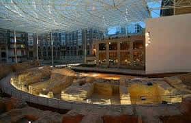 Interior del museo con iluminación nocturna que resalta las estructuras arqueológicas bajo techo moderno