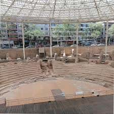 Teatro romano al aire libre con gradas semicirculares y cubierta de estructura metálica transparente