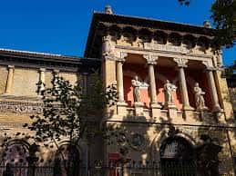 Fachada del Museo de Zaragoza bajo cielo azul con árboles en primer plano