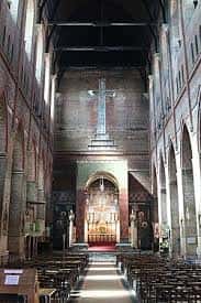 Interior de la nave central con bancos, altar y cruz sobre el presbiterio