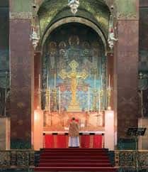 Altar principal con mosaico dorado y sacerdote celebrando misa