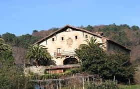 Vista exterior de la escuela Igeldo Herri Eskola en San Sebastián con fachada tradicional y entorno natural