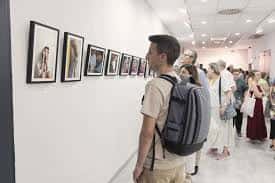 Interior de la sala de exposiciones con visitantes observando obras enmarcadas