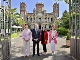 Vista frontal del edificio histórico con cuatro personas posando en la entrada