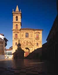Fachada lateral de la iglesia al atardecer con torre y cielo azul