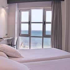 Habitación con cama doble y ventana con vista al océano