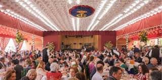 Interior de la caseta del Real Círculo de Labradores durante una fiesta con decoración festiva y gente celebrando