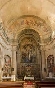 Vista del interior de la capilla con bóveda decorada y bancos de madera