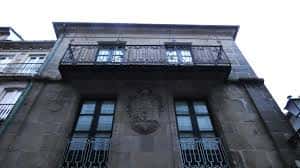 Detalle superior de la fachada del Pazo con balcón de hierro forjado y escudo heráldico