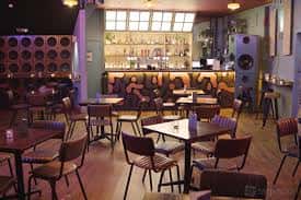 Interior del Dead Wax Social con mesas, sillas y barra de bebidas
