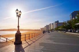 Paseo marítimo de San Lorenzo al atardecer con farolas y edificios al fondo