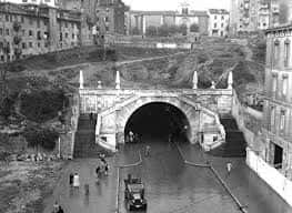 Fotografía histórica en blanco y negro del túnel con tráfico antiguo y edificios circundantes