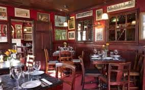 Interior acogedor del restaurante con mesas dispuestas y decoración tradicional en tonos rojos y madera oscura