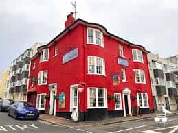 Fachada exterior del establecimiento Lion & Lobster en Brighton, edificio rojo con arquitectura clásica y letreros visibles