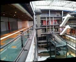 Interior del centro comercial con escaleras mecánicas y diseño arquitectónico moderno