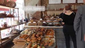 Interior del mostrador de panadería con productos frescos y personal atendiendo
