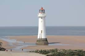 Faro de New Brighton en un día soleado con personas en la playa