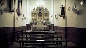 Interior de la capilla del convento con altar barroco y bancos de madera