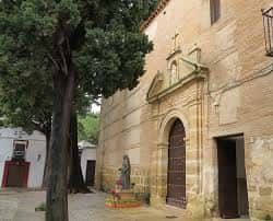 Fachada exterior del convento con entrada arqueada y árbol frondoso