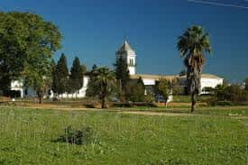 Vista panorámica del Cortijo de Cuarto con su torre y jardines bajo cielo despejado