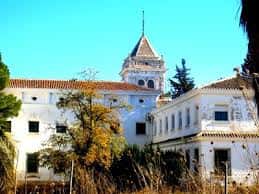 Fachada lateral del cortijo con torre campanario y vegetación mediterránea