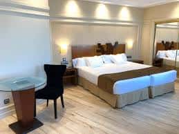 Habitación doble moderna con cama king-size, escritorio y suelo de madera clara