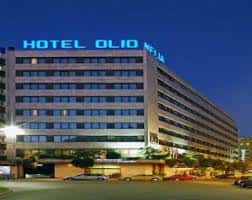 Fachada exterior del Hotel Olid de noche con letrero luminoso azul