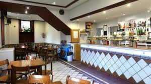 Interior del bar con barra de servicio y mesas de madera