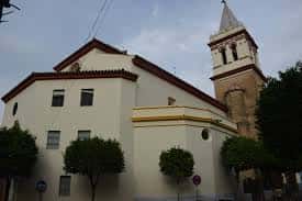 Vista exterior de la Iglesia de San Gil Abad con su torre campanario y fachada blanca